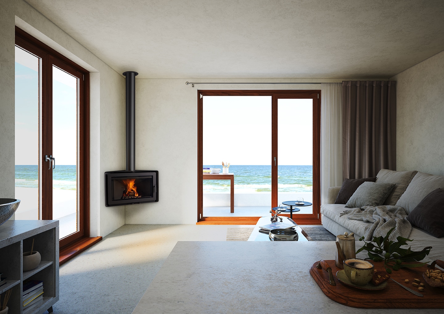 Un salon moderne avec un poêle à bois Rocal, un canapé et une table basse. De grandes portes vitrées s'ouvrent sur un patio donnant sur l'océan. La pièce présente un ANGLE de design minimaliste avec des murs et des sols de couleur claire. La lumière du soleil pénètre à travers les portes, renforçant la sensation d'espace.